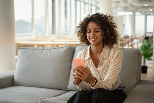 Young indian business woman texting on mobile phone in coworking office lounge, using smartphone app. In 30s, female manager works as executive, entrepreneur, owner, ceo, boss, leader. Copy space