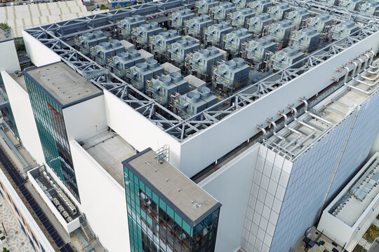 Aerial view of a modern data center facility featuring extensive rooftop cooling units, complex HVAC infrastructure, and industrial metal framework in the United Kingdom.