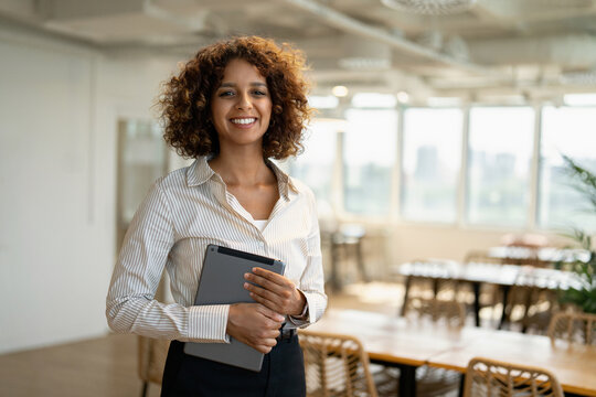Middle eastern business woman browsing on digital tablet in coworking office workplace, using touchscreen. In 30s, female manager works as executive, entrepreneur, owner, ceo, boss. Copy space