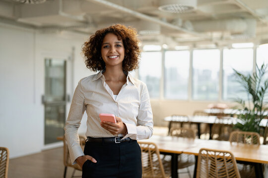 American business woman texting on mobile phone in coworking office workplace, using smartphone app. In 30s, female entrepreneur works as owner, ceo, boss, leader, specialist, consultant, director