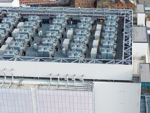 Aerial view of a data center roof featuring numerous industrial cooling units, ventilation systems, and complex piping infrastructure in the United Kingdom.