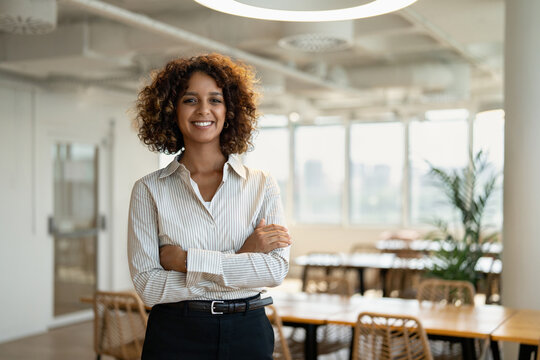 Latin business woman standing for portrait in coworking office workplace, looking at camera. In 30s, female professional works as businesswoman, manager, executive, entrepreneur, owner. Copy space