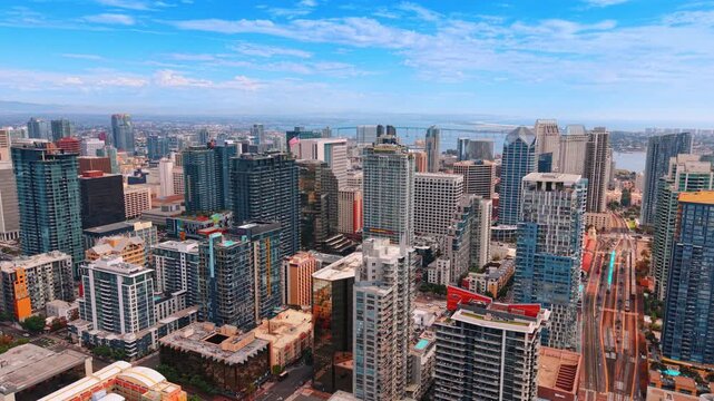 Glass residential towers and downtown streets in San Diego. Sunlight falls across balconies and office facades above a dense grid of San Diego buildings.