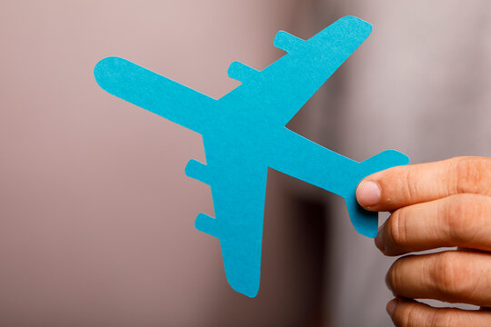 Blue paper airplane held by a hand, symbolizing travel, adventure, and global connection.