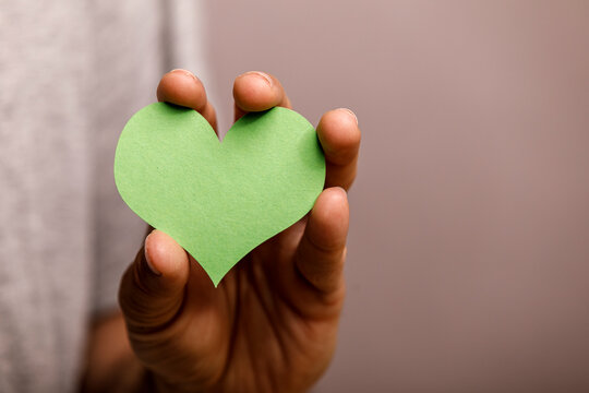 A close-up of a hand presenting a vibrant green heart, representing environmental care.