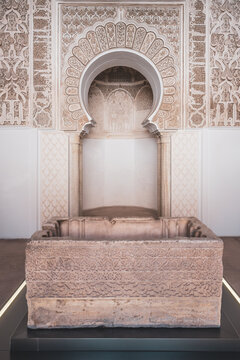 People gather in the Prayer Room of Madrasa Ben Youssef in Marrakesh, Morocco. They admire the architecture and intricate designs. The room is a key place for cultural learning.