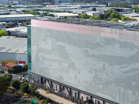 Aerial view of a modern data center building featuring a large patterned facade and glass elements situated within an industrial park, United Kingdom.