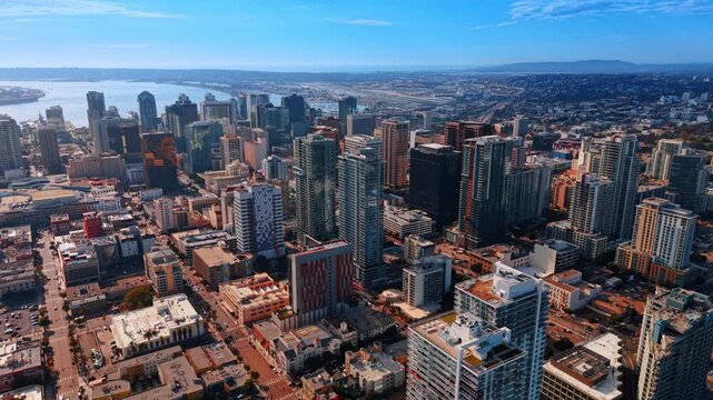 San Diego towers and neighborhoods along the bay. Rows of buildings rise above streets near San Diego Bay, with hills and suburbs in the distance.