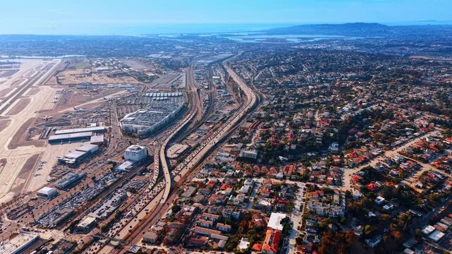 San Diego airport beside a freeway and residential neighborhoods. Parallel transport corridors run between airport grounds and rows of homes on the hills of San Diego.