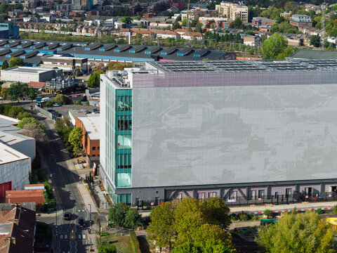 Aerial view of a modern data center building with a large grey facade and glass windows, situated in an urban area with surrounding streets and trees in the United Kingdom.