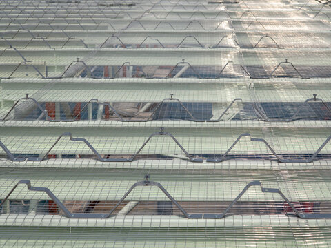 Closeup of galvanized steel roof purlins with wire safety mesh, insulation support net, roof spacers and clip lock brackets during an industrial warehouse roofing system installation and construction.