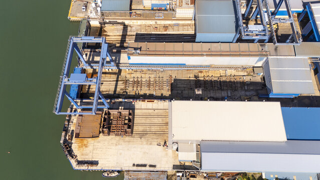 Aerial view of the industrial port area in Zumaia, featuring large gantry cranes, storage yards, and warehouse structures along the waterfront in Zumaia, Basque Country, Spain.