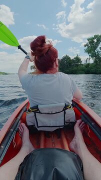 Redhead Woman Paddling Orange Kayak on River with Point of View Perspective on Sunny Day