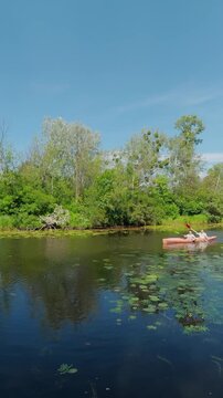 Mature couple paddling tandem kayak on calm river in summer forest concept of active retirement