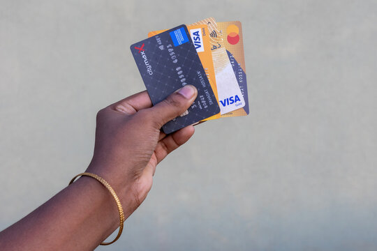 Kishoreganj, Bangladesh - 26 September, 2026 - Person hand holding multiple bank credit and debit cards outdoors. Financial payment cards display.