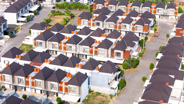 Aerial view of a modern residential housing complex with uniform houses featuring dark roofs and paved streets in Semarang, Central Java, Indonesia.