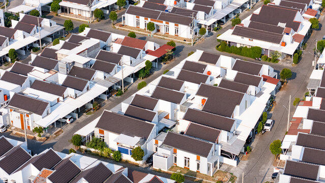 Aerial view of a modern residential housing complex with white houses, dark roofs, and paved streets in Semarang, Central Java, Indonesia.
