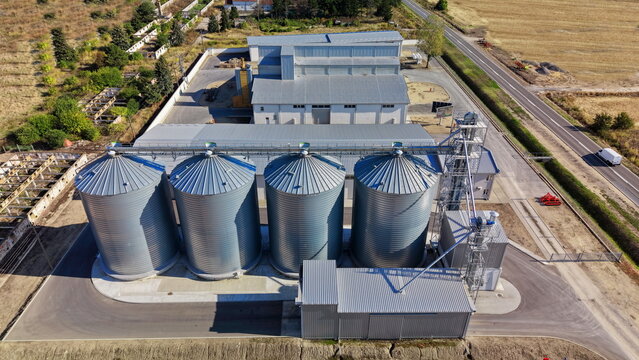 Aerial view of the storage silo Bavaniste facility featuring four large metal grain silos and a processing building surrounded by fields in Bavaniste, Vojvodina, Serbia.