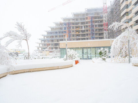 City landscape transforming under thick snow, showing ongoing building construction