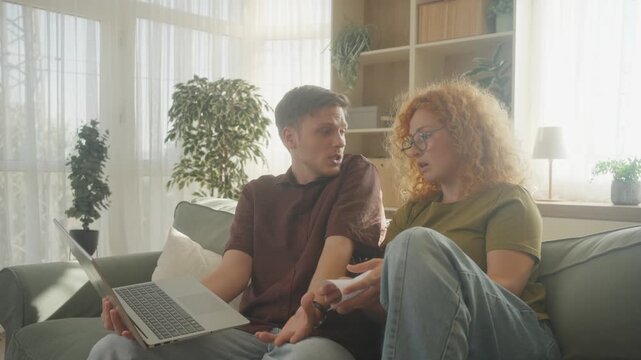 Focused Gen Z couple managing household finances and unpaid bills at home. Young family faces financial crisis, debt and rising living costs.