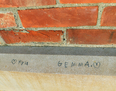 Red brick wall with vintage stone lintel showing carved inscription
