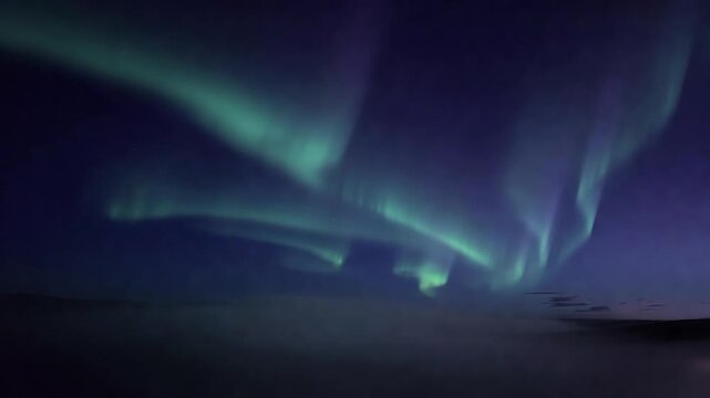 Dancing northern lights illuminating the arctic night sky above the clouds. Beautiful green and purple aurora borealis phenomenon