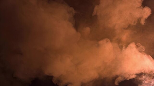 Orange smoke cloud swirling and billowing on a dark background. Abstract atmospheric fog, dust, or mist creating a dynamic effect