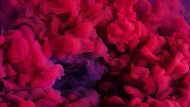 Swirling pink and purple ink mixing in water creating a beautiful abstract cloud formation against a dark background