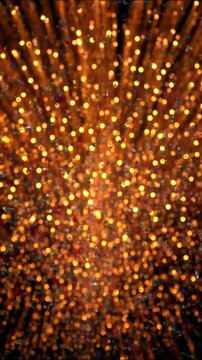 Golden confetti and glitter exploding on black background. Celebration abstract animation with glowing particles and bokeh effect