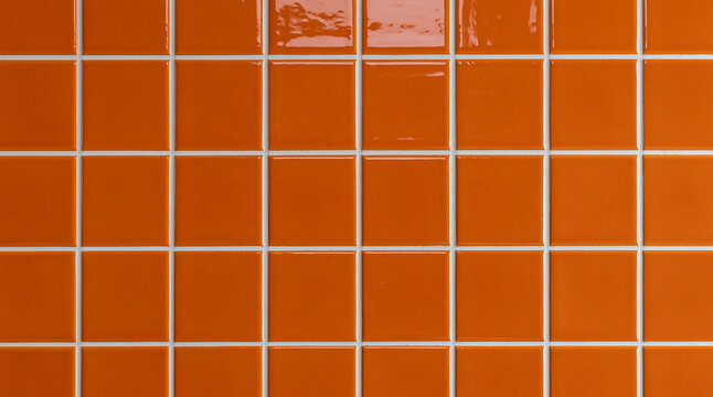 Glossy orange square ceramic tiles with white grout create a vibrant wall pattern. Perfect background texture for interior design and modern architecture projects.