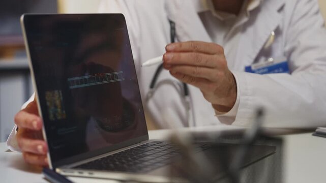 Doctor explains DNA mutation on laptop during medical consultation in clinic
