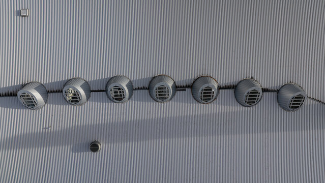 Aerial view of a corrugated metal shopping mall roof featuring a row of circular skylights in Iceland.