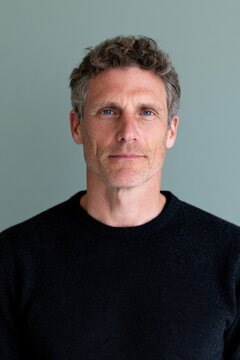 Clean studio portrait of a middle aged man with blue eyes and casual sweater for professional headshot and profile background