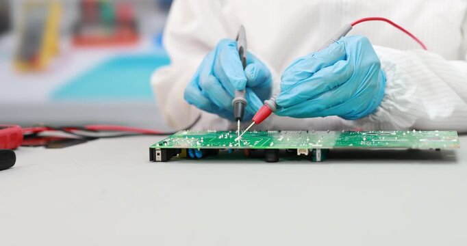 Close-up of a technician in protective gloves testing a green circuit board with multimeter probes on a workbench.