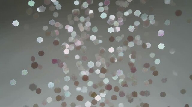 Drifting hexagonal highlights originating top center, falling past focal plane across gray backdrop