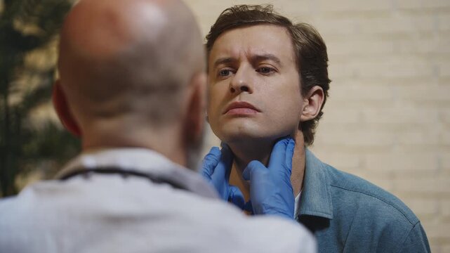 Physician performs male patient's neck examination during ENT medical visit