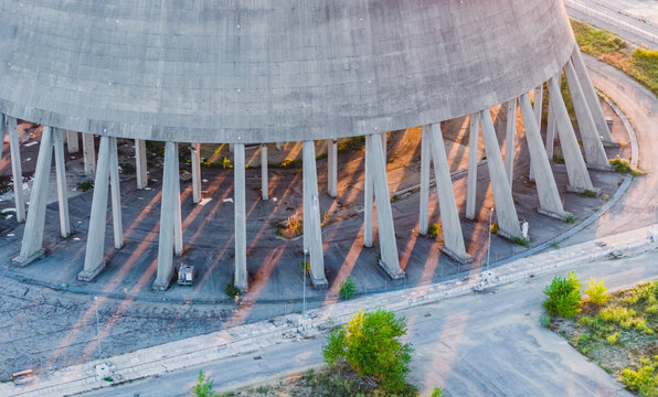 Aerial view of the massive concrete base and support columns of an industrial cooling tower in evening sunlight in Trino, Piedmont, Italy.