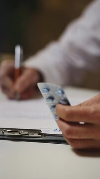 Male doctor prescribes medication to patient during check-up, holding pills
