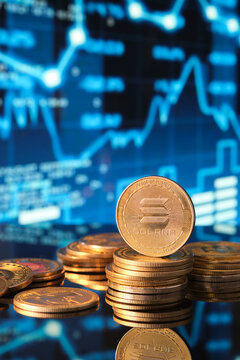 Solana Cryptocurrency Coins Stacked on a Table With Trading Graphs in Background