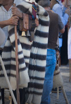 Shepherds holding wooden crooks and striped wool blankets with cowbells at a transhumance festival in Serra da Estrela, Portugal