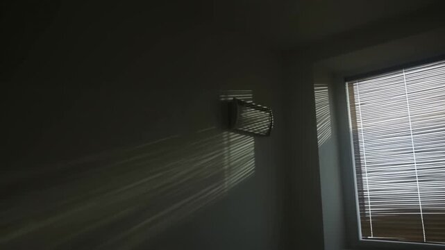 Sunlight passes through venetian blinds across a dark interior wall. Interior design presentations, home decor advertising, and lifestyle storytelling.