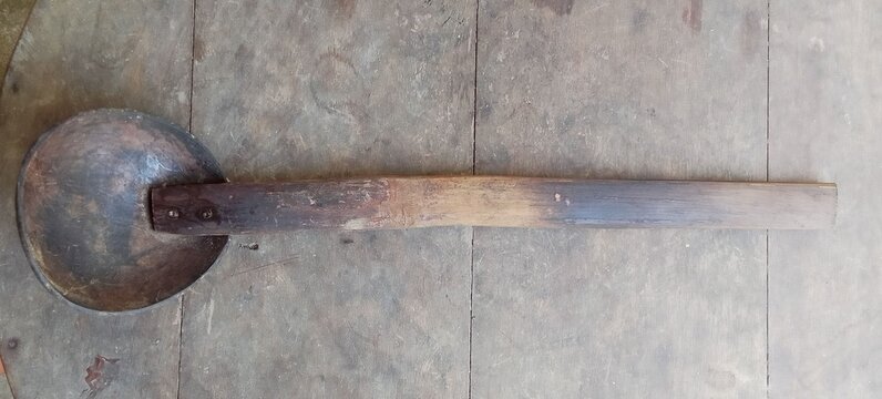 Front view of antique traditional Javanese palm sugar ladle irus Jawa, vintage coconut Shell ladle with long wooden handle showing interior bowl 