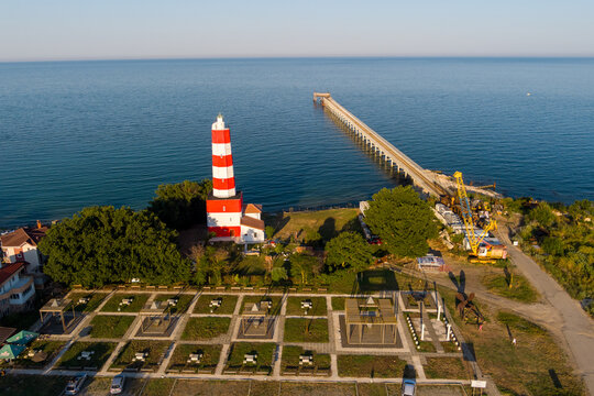 Aerial view of the red and white striped lighthouse, a long pier extending into the Black Sea, and a landscaped park in Saints Constantine and Helena, Varna, Bulgaria.
