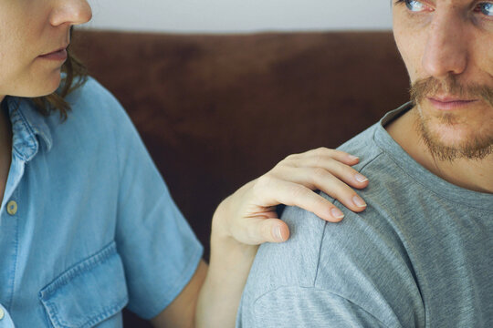 Close-up of woman gentle touching man's shoulder as he turns toward her. Symbolizes communication initiative, attempt at reconnection, partner responsiveness, and relationship healing.