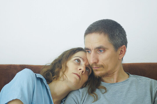 Woman rests head on man's shoulder and looks at him while he gazes away. Shows emotional exhaustion after conflict, relationship healing, and silent togetherness between partners navigating difficulty