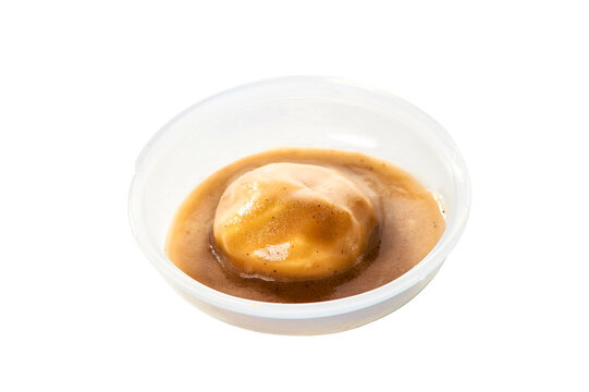 Still-life photography of mashed potatoes with black pepper gravy on a white background.