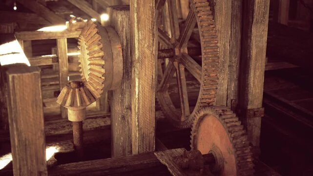 Close up wooden gear teeth and aged mechanism showing wear, visible grain, oil residue and tooth pattern, tactile craftsmanship captured in tight frame.