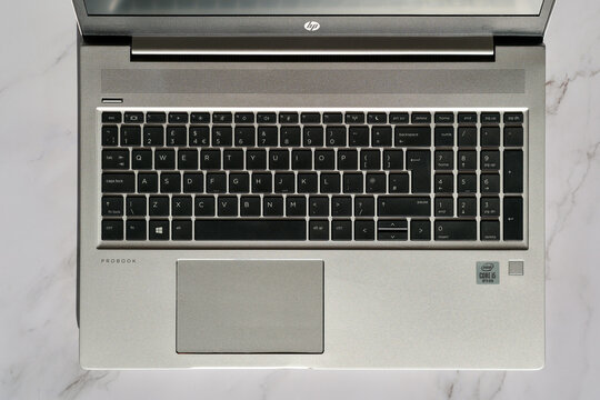 Top down architectural view of an open HP ProBook laptop computer featuring a full black keyboard and Intel Core i5 processor sticker resting on a bright white marble desk workspace.