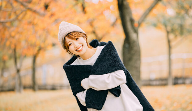 秋の紅葉とニット帽を被った笑顔の女性