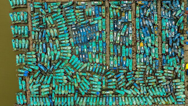 Aerial view of Malpe Fishing Harbour with numerous turquoise fishing boats docked in a dense grid pattern in Udupi, Karnataka, India.